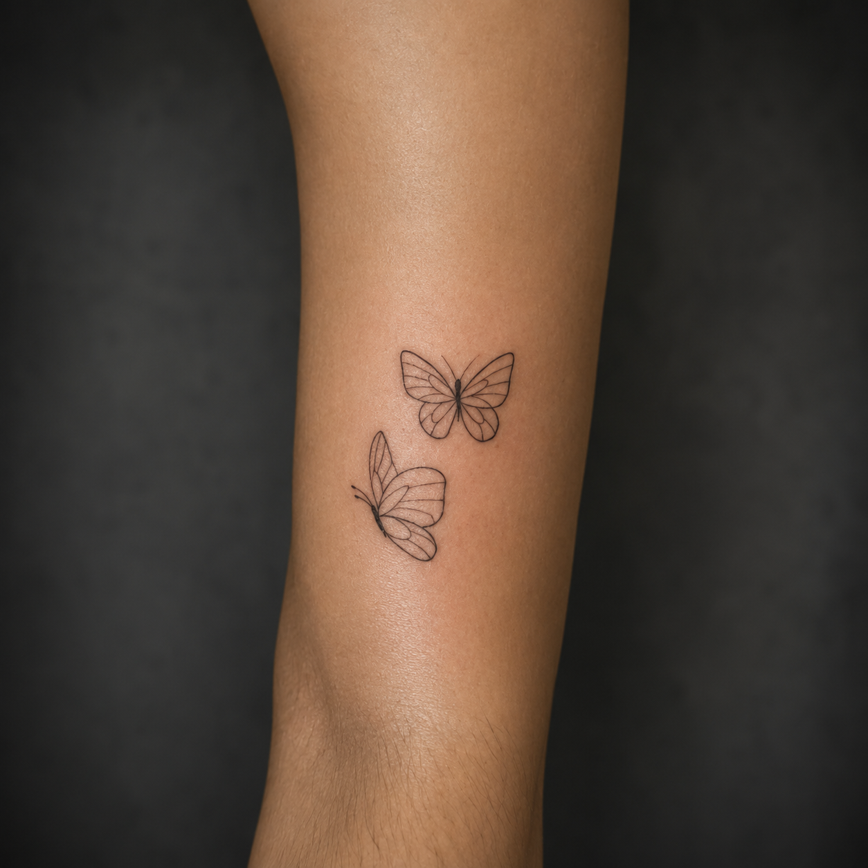Tatuagem fine line de duas borboletas no antebraço